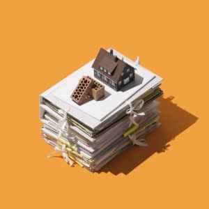 Home construction and real estate: pile of paperwork, bricks and model house